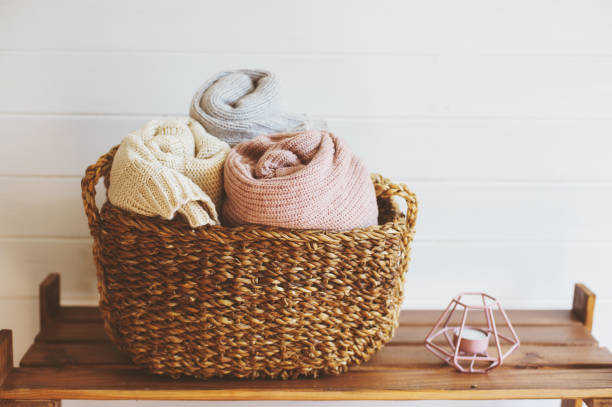 cozy interior details, scandinavian mininalistic lifestyle. Organizing clothes in wicker backets, seasonal wardrobe and house cleaning, ideas for winter season. stock photo