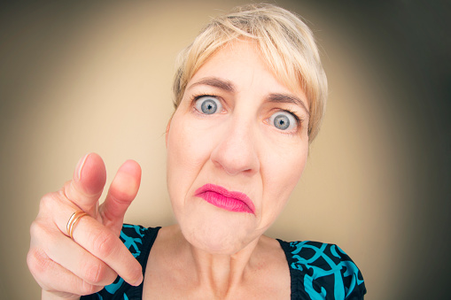 A humorous fisheye image of a karen-type of woman with a crabby expression pointing her finger.