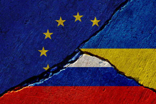 cracked concrete wall with painted eu, russia and ukraine flags stock photo