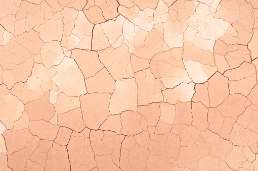 Top view of cracked dry soil ground with peach and red-pink color in drought season
