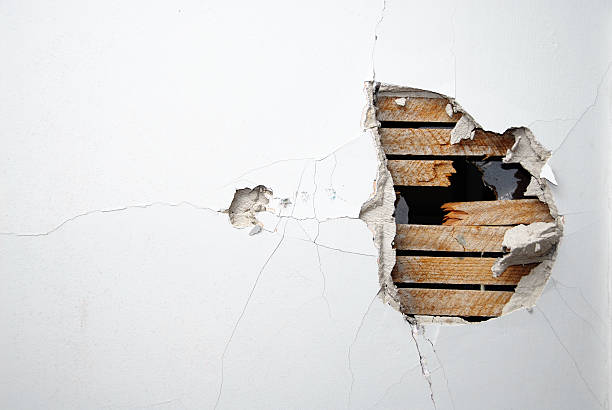 cracked plaster, drywall and wood of a home's white wall - gat stockfoto's en -beelden