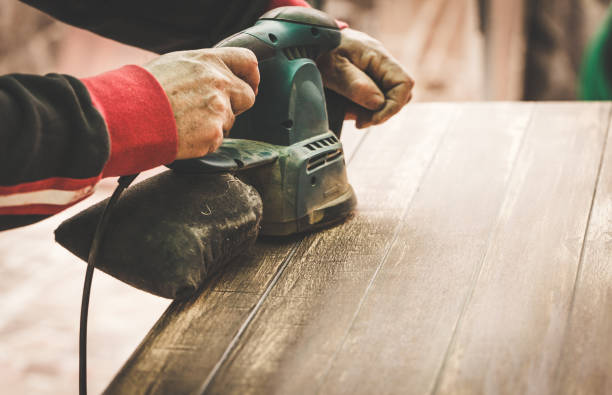 Craftsman hands polishing old color from wooden table with machine. Toned Image. stock photo