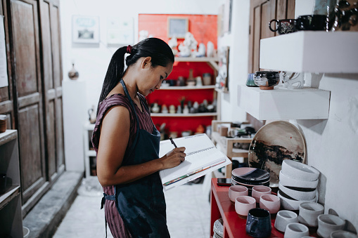 Shot of a confident young woman doing inventory in a pottery studio