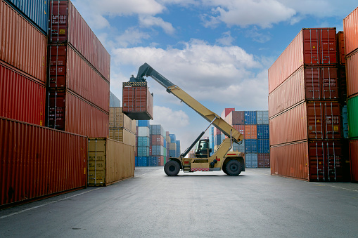 Forklift lifting up container in commercial port.