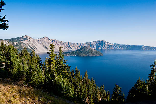 Crater Lake and Wizard Island Crater Lake exists in the blown-out caldera of a once mighty volcano known as Mount Mazama. This view of the lake and Wizard Island was taken from the West Rim Drive in Crater Lake National Park, Oregon, USA. jeff goulden crater lake national park stock pictures, royalty-free photos & images