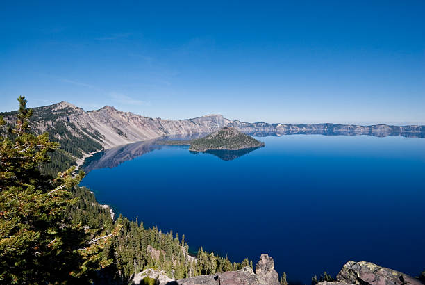 Crater Lake and Wizard Island Crater Lake exists in the blown-out caldera of a once mighty volcano known as Mount Mazama. This view of the lake and Wizard Island was taken from the Rim Trail in Crater Lake National Park, Oregon, USA. jeff goulden crater lake national park stock pictures, royalty-free photos & images