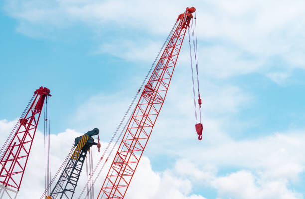 Crawler crane against blue sky and white clouds. Real estate industry. Red crawler crane use reel lift up equipment in construction site. Crane for rent. Crane dealership for construction business. stock photo