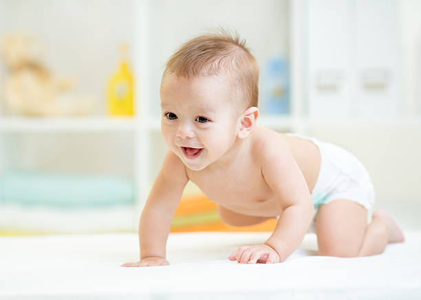 crawling baby baby boy weared diaper crawling on bed at nursery crawling stock pictures, royalty-free photos & images