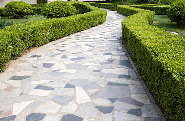 Crazy paving path winding between hedges in a Beijing park Crazy paving footpath in a park in Beijing, China with hedges on either side garden path stock pictures, royalty-free photos & images