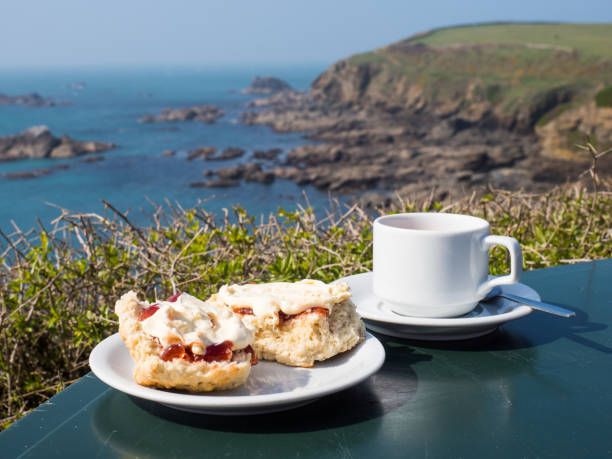 Cream tea Cornish cream tea, including scones with jam and clotted cream, with a seascape background at Lizard Point, Cornwall, England. lizard photos stock pictures, royalty-free photos & images
