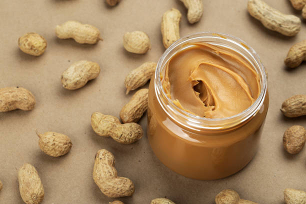 Creamy and smooth peanut butter in jar on paper table. stock photo