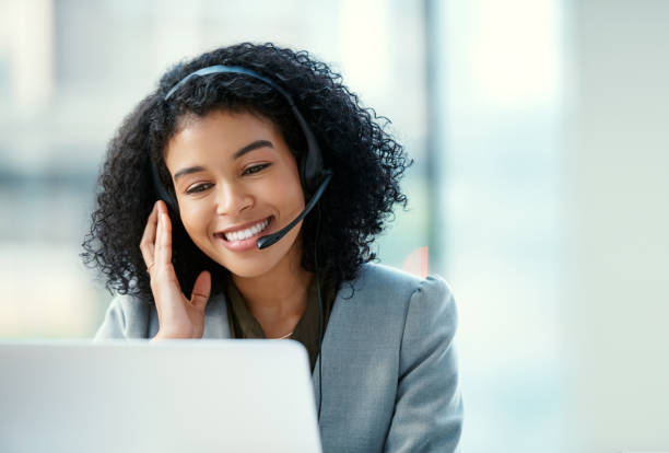 Creating happy customers makes her smile Shot of a confident young woman using a headset and laptop in a modern office headset woman customer service stock pictures, royalty-free photos & images