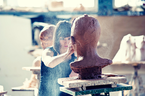 Beautiful young sculptor creates a clay sculpture