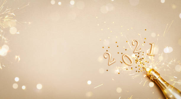 Creative Christmas and New Year greeting card with golden champagne bottle, confetti stars and 2021 numbers. Flat lay. Banner format. Creative Christmas and New Year greeting card with golden champagne bottle, confetti stars and 2021 numbers. Modern flat lay. Banner format. 2021 stock pictures, royalty-free photos & images
