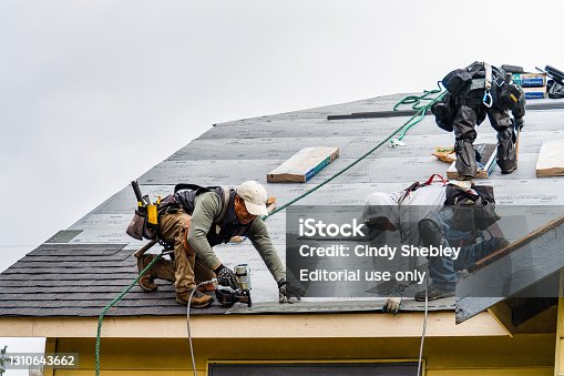 istock Crew Installing New Shingles on Roof on a Rainy Day 1310643662