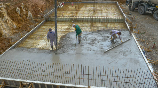 A crew of contractors pours concrete over metal wiring placed on ground floor. stock photo