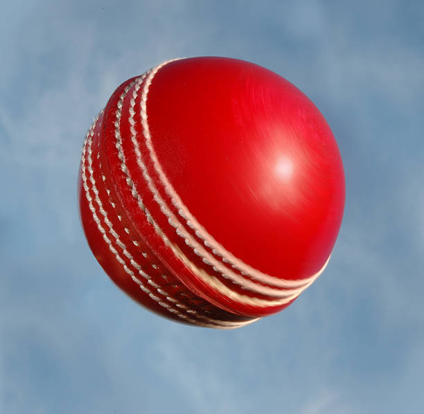 Cricket ball spinning against sky stock photo