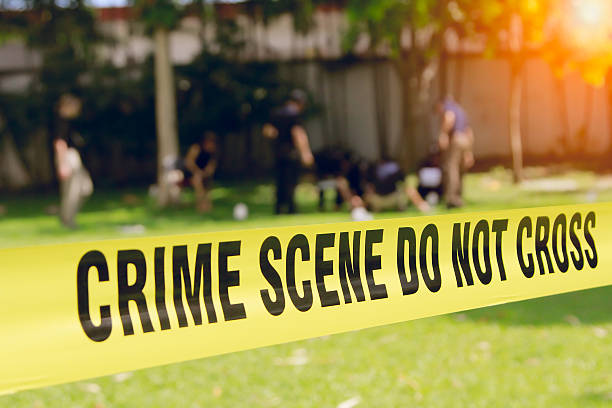 crime scene tape and blurred law enforcement team background stock photo