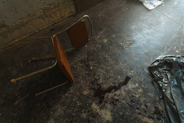 A crime scene with a fallen chair and a blood spot in an abandoned room stock photo