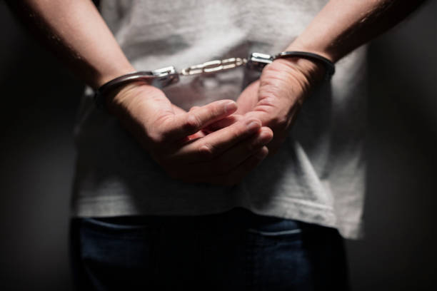 Criminal in handcuffs Arrested man in handcuffs with handcuffed hands behind back sentencing stock pictures, royalty-free photos & images