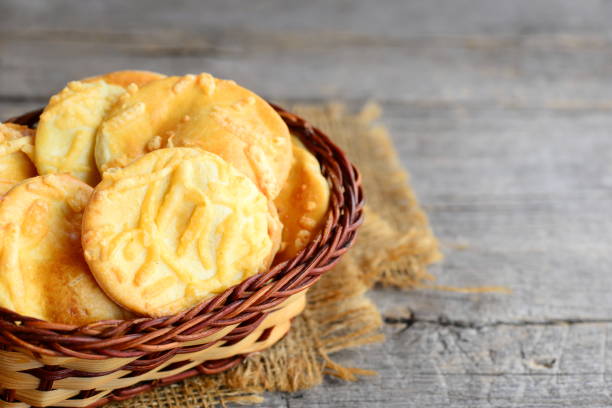 Crispy cheese cookies. Homemade baked cheese cookies in a wicker basket on a vintage wooden background. Closeup stock photo