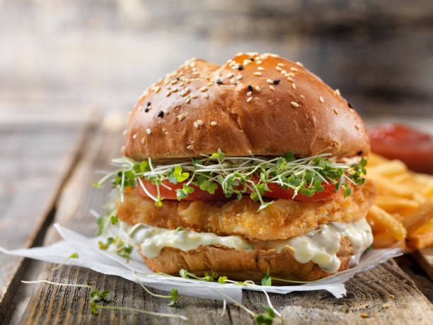Crispy Fish Burger with Tarter Sauce, Lettuce, Tomato on a Brioche Bun Crispy Fish Burger with Tarter Sauce, Lettuce, Tomato on a Brioche Bun salmon seafood photos stock pictures, royalty-free photos & images