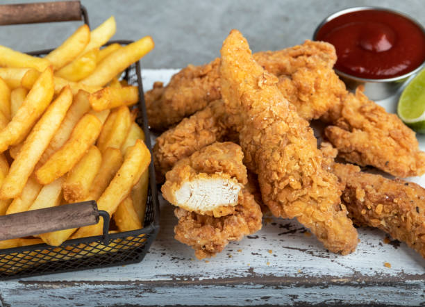 crispy fried breaded chicken breast strips french fries and sauce stock photo