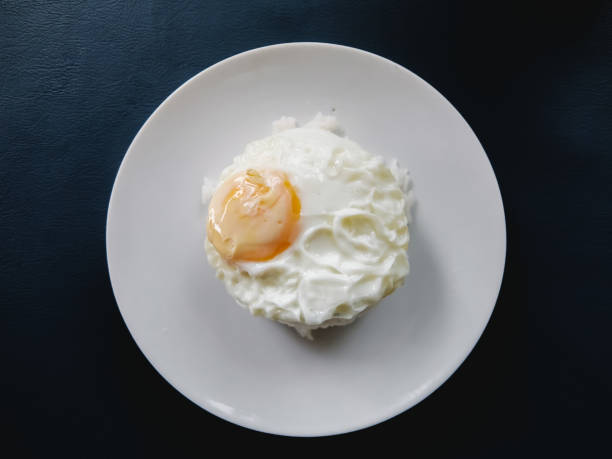 Crispy fried egg Put on steamed rice in a white dish Ready to eat for breakfast, Placed on a blue leather table stock photo