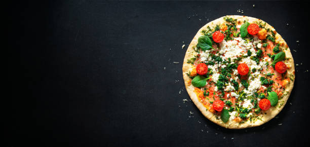 Crispy spinach pizza with ricotta, mozzarella and tomatoes stock photo