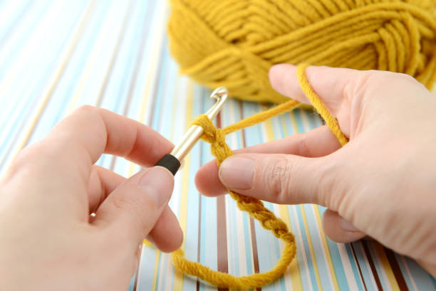 crocheting with brown wool in hand. stock photo