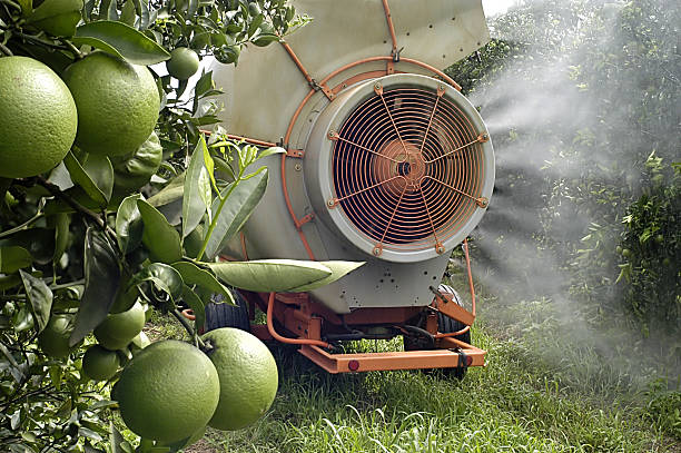 A crop sprayer on some fruit trees stock photo