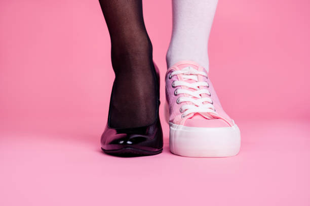 裁剪特寫鏡頭圖像概念照片兩個不同的適合薄苗條的腿舒適舒適豪華優雅別致的運動相比較鞋具隔離在粉紅色的柔和背景 - 差異 個照片及圖片檔