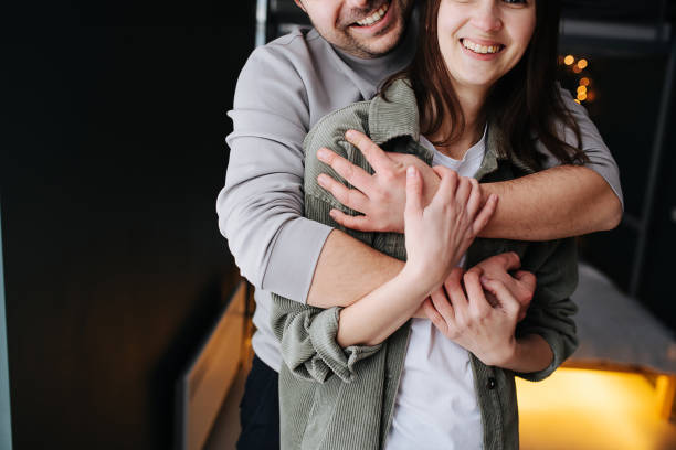 Cropped image of a happy loving couple. Man hugs woman from behind. stock photo