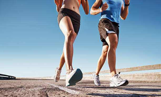 cropped image of couple jogging - hardlopen vorouw stockfoto's en -beelden