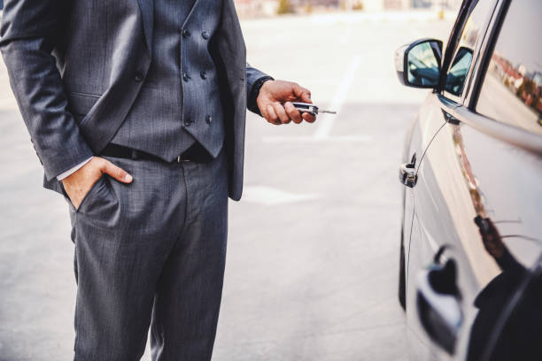 Cropped picture of elegant businessman standing next to his car and holding keys.  man driving suit stock pictures, royalty-free photos & images