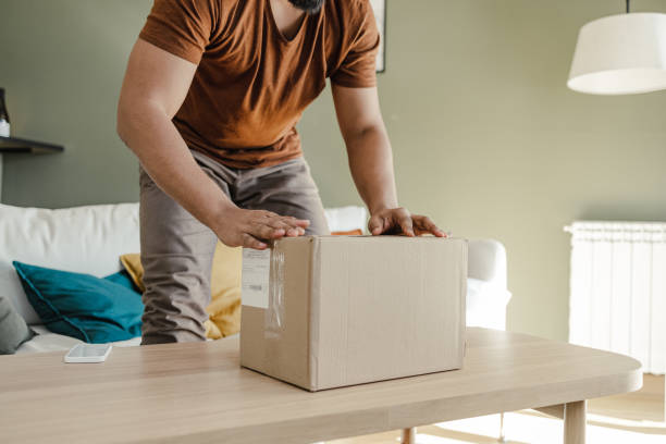 Cropped shot of a young man unpacking online purchase stock photo
