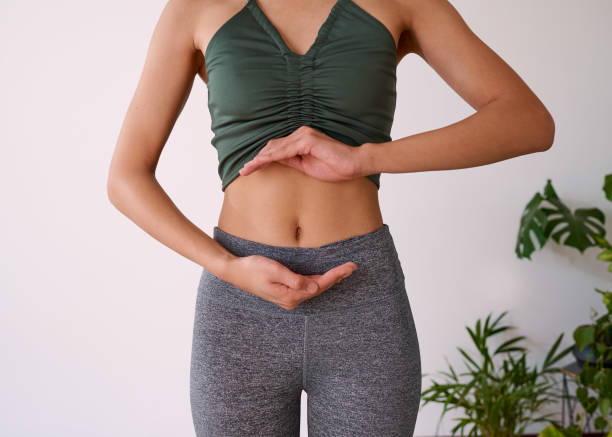 Cropped shot of a young multi-ethnic woman's stomach cupped by her hands stock photo