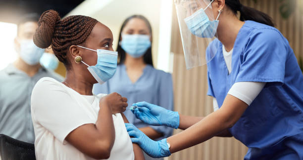 Cropped shot of an attractive young businesswoman getting her covid vaccination from a female nurse in the office stock photo