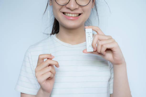 Cropped shot of Asian woman holding a disposable sterile flocked swab with a test pad before doing swab by herself. stock photo