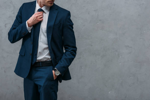 cropped shot of handsome businessman in stylish suit in front of concrete wall cropped shot of handsome businessman in stylish suit in front of concrete wall handsome people stock pictures, royalty-free photos & images