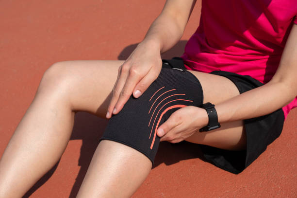 Cropped shot of runner woman suffering from knee pain and she wearing knee braces for supports to be worn when you have pain in your knee. stock photo