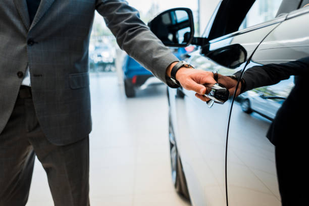 cropped view of man opening car door in car showroom cropped view of man opening car door in car showroom open car door stock pictures, royalty-free photos & images