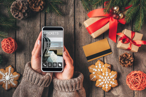cropped view of woman using smartphone with ticket app on wooden background with credit card and christmas presents - smartphone christmas imagens e fotografias de stock