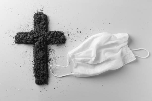 Cross and medical mask, the concept of memory of people who died during the global epidemic of covid-19 viral infection. Ash Wednesday is a religious concept. stock photo