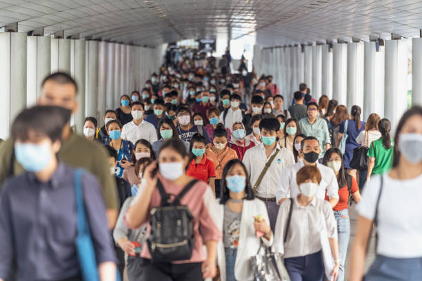 コロナウイルスの流行を防ぐために外科用マスクを着用した認識できないビジネスマンの群衆 - 通勤 ストックフォトと画像