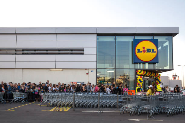 Crowd waiting in queue for the grand opening ceremony of the 1st Lidl supermarket in Serbia. Lidl is a German global discount supermarket chain Picture of a Lidl sign in their main shop in Belgrade, Serbia, with a huge waiting queue in front during the first operational day. Lidl is a discount supermarket chain, based in Germany, operating more than 10,000 stores across Europe. The brand opened its first stores in Serbia on the 11th of October, thus generating huge affluence and crowd to visit the stores on their first days of operation lidl stock pictures, royalty-free photos & images
