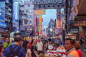 Bangkok, Thailand - June 2, 2019: a diverse crowd walks along Yaowarat Road with its Chinese and Thai signboards in the evening. Yaowarat Road is the main artery of Chinatown, a popular tourist attraction.