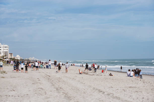 Crowds at beach to watch SpaceX rocket launch in Florida Indialantic, Florida, USA - January 19, 2020: People stand on a beach and look up the coast toward Cape Canaveral as a SpaceX Falcon 9 rocket launches into the sky (barely visible on the right, just above the horizon). More people than usual came out to view this launch, as the rocket would separate 84 seconds into flight and then explode as part of a planned test of the Crew Dragon astronaut capsule. nasa spacex launch rocket stock pictures, royalty-free photos & images