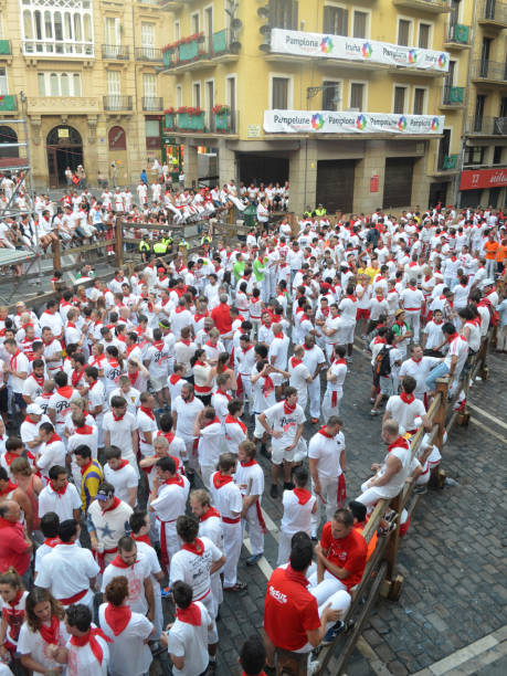 Crowds in traditional white shirts and red neck ties line the streets of Pamplona during the annual San Fermin festival. Basque country, Spain. stock photo