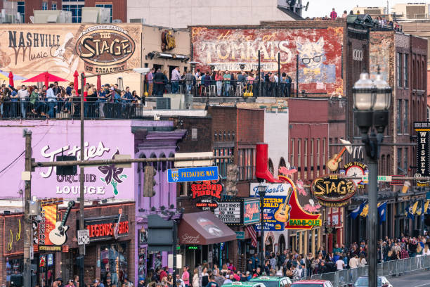 Crowds of people walking past the bars and Venues lining Broadway. Nashville, Tennessee - March 23, 2019 : Crowds of people walking past the bars and Venues lining Broadway. broadway nashville stock pictures, royalty-free photos & images